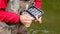 A fisherman selects a fly in a case on a hook. Fly fishing. Hands of an elderly man close-up. Sport and hobbies.