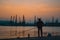 Fisherman silhouette at the docks in the harbor at golden sunset hour.