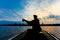 Fisherman silhouette with fishing rod in the inflatable boat at sunrise and throws a lure for catching fish