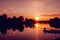 Fisherman silhouette on sunset background. Friends fishers enjoy fishing on river pier.