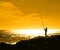 Fisherman silhouetted against an orange sky