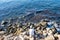 Fisherman sitting on rocks with two fishing rods.  Blue sea background, above view