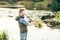 Fisherman with a spinning rod catching fish in a river