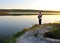 A fisherman standing on the lake shore