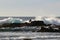 Fisherman standing on the pier on the background of high ocean waves.