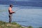 Fisherman stands on the river bank and holds a fishing pole