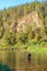 A fisherman stands in the water and fishes in a mountain river.