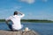 Fisherman thinks how to catch fish on a river in sunny weather