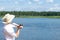 Fisherman throws a fishing rod on the river against the backdrop of a beautiful blue sky