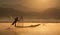 Fisherman with traditional network on the old boat at dawn to