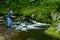 Fisherman trout fishing a small clear stream.