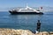 A fisherman watches a cruise ship move through Antalya Bay in Turkey.