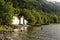 Fisherman in water Norwegian Fjord with boatshed and forest in background