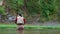 A fisherman in a waterproof suit stands in the water with a fishing rod in his hands. A middle-aged man is fly fishing in a mounta