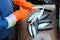 Fishermans hands in orange gloves gutting a small fish. Pullint the roe and guts out is necessary step in fish processing.