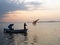 Fishermans throwing net to sea on sunset