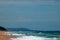 FISHERMEN ON THE BEACH FACING WHITE BREAKERS ROLLING IN.