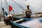 Fishermen clean their fishing nets against the backdrop of massive Chinese fishing structures