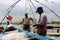 Fishermen clean their fishing nets against the backdrop of massive Chinese fishing structures