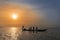 Fishermen collecting the nets in an old traditional fishing canoe near the island of Orango at sunset.