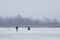 Fishermen figures on little, natural, frozen winter lake, covered with snow, fishing rod and ice auger in hands