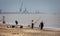 Fishermen fishing off the beach with cranes in Yarmouth Harbour in the back ground, near Lowestoft, Norfolk, UK