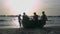 Fishermen Haul Round Boat to Beach against Sunset