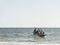 Fishermen inside canoes at sea paddling against the tide