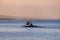 A fishermen`s boat crossing a calm sea near Maumere, Indonesia There are three men in one small, blue boat, one of them is