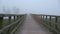 Fishermen silhouette and crow in misty morning on wooden lake bridge