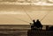 Fishermen silhouettes at the sunrise on the dock