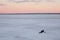 Fishermen sitting on a frozen river at a beautiful sunset frosty day. Winter fishing on the Volga river