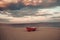 Fishermens boat at seacoast, on sand at sunset with horisont sea on background. Background of sea with waves and sky