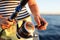 Fisherwoman holds fishing rod in her hands, sea in background.