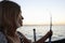 Fisherwoman holds spinning rod in her hands and looking at sea while fishing from boat.