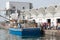 Fishing boat arrived to port full of fish, fishermen moving frozen fish in plastic boxes to harbour