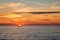 Fishing boat on the background of incredible golden sunrise, clouds and rising sun.