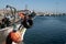 Fishing boat docked in harbor with tyre and bright orange buoy hanging from bow