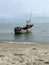 Fishing boat leaning on a sandy beach with blue sky and calm waves