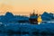 Fishing boat navigates glacier-filled waters at sunset