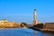 Fishing boat pass by famous Lighthouse and walls of old port, Firka fortress, Old Venetian harbour of Chania, Crete