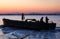 Fishing boat retuning home at sunset with evening sky with waves