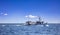 Fishing boat return. Trawler sails in Aegean rippled sea, blue sky background. Cyclades Greece