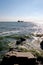 Fishing boat in the sea near the horizon, surf hits the rocks