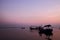 Fishing boat silhouette with orange sunrise sky and water reflection