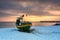 Fishing boat on snowy beach in Gdynia Orlowo at sunrise, Baltic Sea. Poland