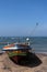 Fishing boat stands on the ocean beach. The Kingfisher bird sitting on a homemade fishing lighthouse on fishing boat.