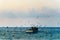 Fishing boat about to go out to sea at dawn, seagulls and clouds.