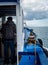 Fishing boat, view of both cabin and sea, being sailed by an old fisherman visible from behind shows hardships of fishermen at sea