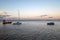 Fishing boats docked at the pier by the shore at sunset. Yachts on the water with colourful sunset sky in the background